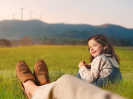 Nachhaltig investieren Mädchen auf Wiese mit Windrädern im Hintergrund